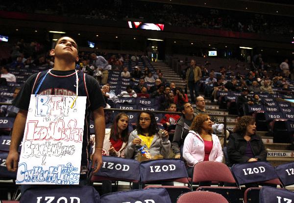 Arlind Lela, 17, of New York, carries a sign commemorating the last New Jersey Nets game to be played at the Izod Center before the start of an NBA basketball game between the Nets and Charlotte Bobcats in East Rutherford, New Jersey April 12, 2010. [Xinhua/Reuters Photo]