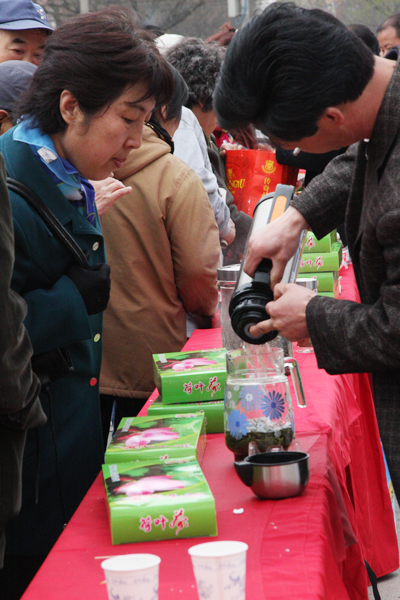 A worker from Yaowan Township makes the local lotus leaf tea for a visitor in Taoranting Park, in Xuanwu District of Beijing, part of the ongoing ancient town gourmet food festival that kicked off in March. [Photo: CRIENGLISH.com]