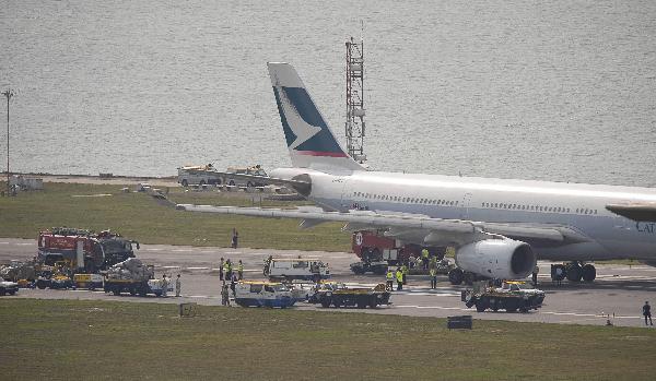 Ground crew and policemen work at the plane at the Hong Kong International Airport in Hong Kong, south China, on April 13, 2010. Seven passengers were injured on a Cathay Pacific plane from Indonesia at the Hong Kong International Airport Tuesday afternoon, when the tyre broke during an emergency landing, according to local authorities. (Xinhua/