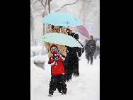 Local residents walk in heavy snow in Harbin, northeast China's Heilongjiang Province, April 13, 2010. [Xinhua]