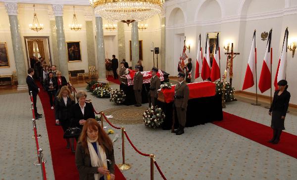 People pay their respects in front of the coffins of the late Polish President Lech Kaczynski and his wife Maria at the President&apos;s Palace in Warsaw April 13, 2010. Poland&apos;s late President Kaczynski and his wife Maria will be buried in the cathedral crypt at Wawel Royal Castle in Poland&apos;s southern city of Krakow on Sunday, a Polish cardinal said on Tuesday. [Xinhua]