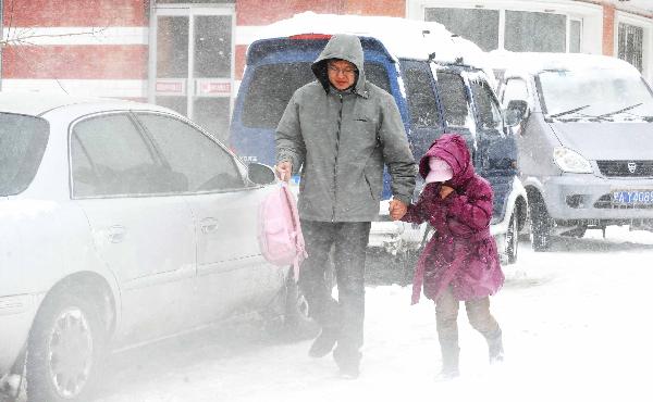  A man walks on the way home with his child in Harbin, capital of northeast China&apos;s Heilongjiang Province, April 13, 2010. The capital city of northeast China&apos;s Heilongjiang Province was hit by the biggest snowstorm of the year on Tuesday, with roads and air traffic disrupted and schools closed.[Xinhua]