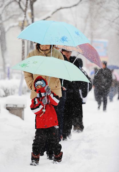 Local residents walk in snow in Harbin, capital of northeast China&apos;s Heilongjiang Province, April 13, 2010.[Xinhua]
