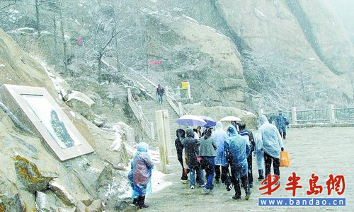 Many tourists climb Mt. Laoshan in the snow to enjoy the extraordinary scenery. [Photo: baodao.cn]