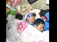 Children sleep in the open air as their parents build up a tent after a quake in Yushu County, northwest China's Qinghai Province, April 14, 2010. About 400 people have died and 10,000 others were injured after a 7.1-magnitude earthquake hit Yushu early on Wednesday. [Xinhua]