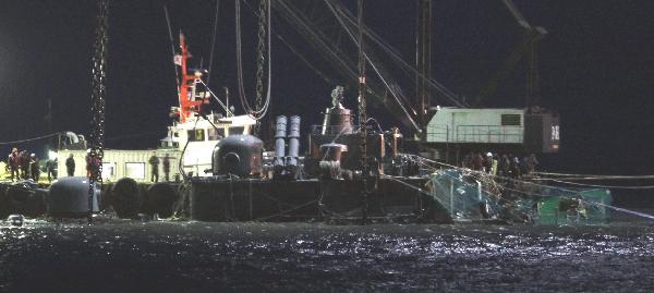 Navy soldiers and salvage team members watch as they cover broken section of the stern of sunken naval vessel Cheonan with nets off Baengnyeongdo island near the maritime border with DRPK, northwest of Seoul April 14, 2010.[Xinhua] 