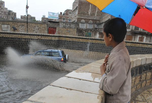 A boy watches a car traveling on a flooded street in Sanaa, capital of Yemen, April 14, 2010. A heavy rain hit the low rainfall Sanaa on Wednesday, causing flooding on the streets. [Xinhua]