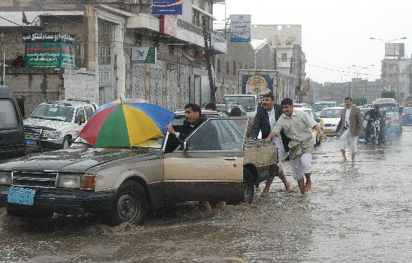 People push a stranded car on a flooded street in Sanaa, capital of Yemen, April 14, 2010. A heavy rain hit the low rainfall Sanaa on Wednesday, causing flooding on the streets.[Xinhua]