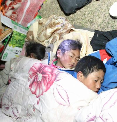 Children sleep in the open air as their parents build up a tent after a quake in Yushu County, northwest China's Qinghai Province, April 14, 2010. About 400 people have died and 10,000 others were injured after a 7.1-magnitude earthquake hit Yushu early on Wednesday.