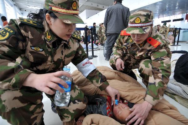 Rescuers from Shenzhen (south China's Guangdong Province) take care of an injured child waiting to get on the plane at Yushu Airport in the 7.1-magnitude-earthquake-hit Yushu County, northwest China's Qinghai Province, April 15, 2010. 