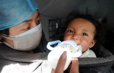 A nurse feeds milk to a baby in a medical shelter in Yushu, the quake-hit area on April 15, 2010.