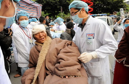 An injured man walks out from medical shelter with the help of a doctor in Yushu, the quake-hit area April 15, 2010.