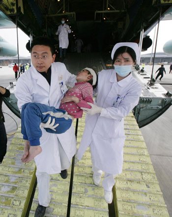 Doctors carry an injured girl off board and rush her to medical treatment in Shuangliu Airport of Chengdu, capital city of Sichuan province April 15, 2010. Some Yushu earthquake wounded people have been transferred to hospitals of neighboring Sichuan province. 