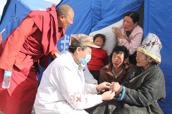 A military doctor cures an elder at a military tent hospital in Gyegu Town of earthquake hit Yushu County of northwest China's Qinghai Province e,April 16,2010.Dozens of medical team have rushed to Yushu from all over China since the 7.1-magnitude quake struck here early Wednesday.(