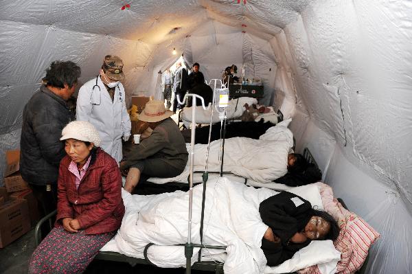 Injured people receive treatment at a military tent hospital in Gyegu Town of earthquake hit Yushu County of northwest China's Qinghai Province,April 16,2010.Dozens of medical team have rushed to Yushu from all over China since the 7.1-magnitude quake struck here early Wednesday.(