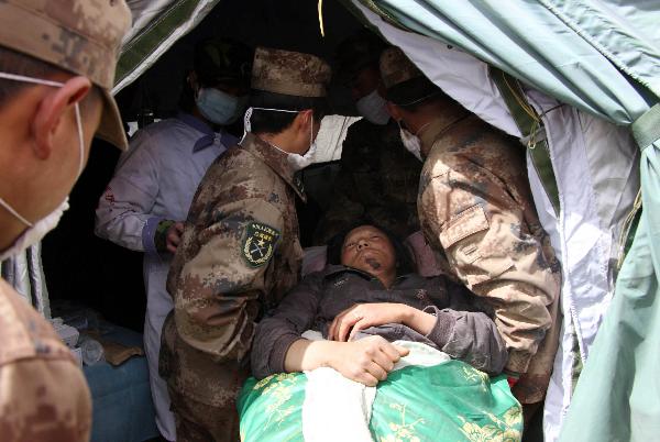 Military doctors move an injured into a military tent hospital in Gyegu Town of earthquake hit Yushu County of northwest China's Qinghai Province,April 16,2010.Dozens of medical team have rushed to Yushu from all over China since the 7.1-magnitude quake struck here early Wednesday.(