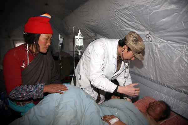 A military doctor checks an injured at a military tent hospital in Gyegu Town of earthquake hit Yushu County of northwest China's Qinghai Province,April 16,2010.Dozens of medical team have rushed to Yushu from all over China since the 7.1-magnitude quake struck here early Wednesday