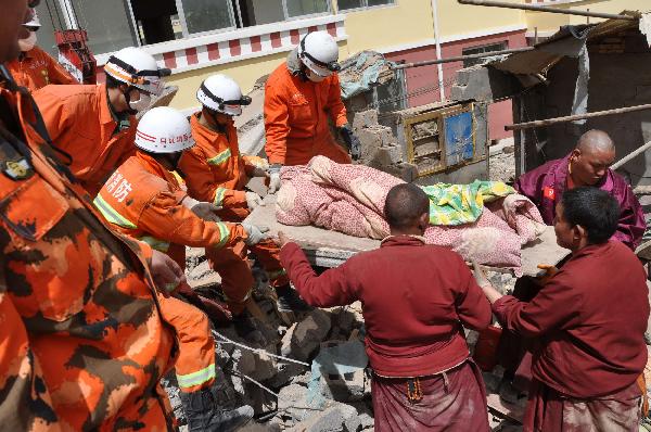 Rescuers of fire fighters and local monks jointly help survivors out of debris in quake-hit Yushu County, Qinghai Province, April 16, 2010. A dragnet serach for survivors is implemented throughly at all rescuing sites as the 'golden 72 hours', a key surviving chance for buried people comes on Friday. Yushu was jolted by a 7.1-magnitude earthquake Wednesday morning, which has left at least 1144 people dead. 