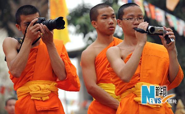Some monks take pictures while watching the Water Splashing Festival celebration in Jinghong City in Dai Autonomous Prefecture of Xishuangbanna, Yunnan Province, April 14, 2010. 