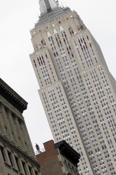 A life-size sculpture by British artist Antony Gormley is placed on the rooftop of a building near the Empire State Building in New York, the United States, April 16, 2010. Thirty one life-size sculptures by British artist Antony Gormley are installed on sidewalks and rooftops of buildings near the Empire State Building as an art display called 'Event Horizon'. 