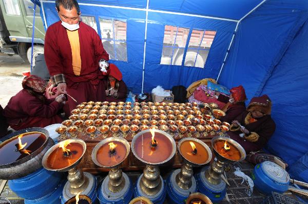 Monks light butter lamps to pray for the quake victims in a tent in quake-hit Gyegu Town of Yushu County, northwest China's Qinghai Province, April 17, 2010.