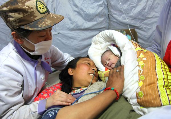 Ga Yong (C), a 22-year-old woman who just gave birth to a baby girl in a tent hospital, looks at her daughter in Gyegu Town, northwest China's Qinghai Province, on April 17, 2010. [Li Gang/Xinhua]