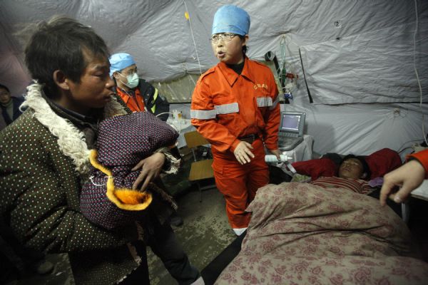 A man holds his newborn child at a makeshift shelter in Gyegu Town, Yushu County, northwest China's Qinghai Province, on April 17, 2010. [Shen Bohan/Xinhua]