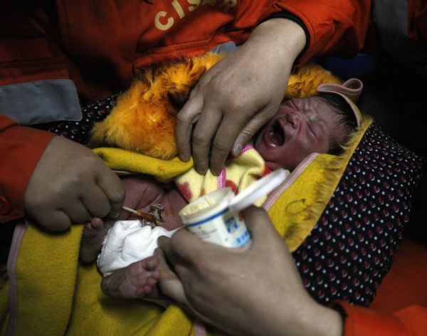 Medical personnel disinfect a newborn baby at a makeshift shelter in Gyegu Town, Yushu County, northwest China's Qinghai Province, on April 17, 2010. [Shen Bohan/Xinhua]