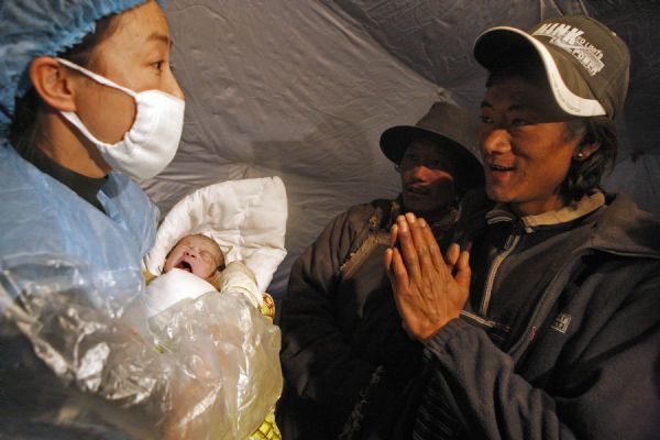 Father of a newborn baby (R) thanks a doctor at a makeshift shelter in Gyegu Town, Yushu County, northwest China's Qinghai Province, on April 17, 2010. [Shen Bohan/Xinhua]