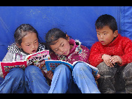 Children read books near a tent in quake-hit area Yushu, Qinghai province, April 18, 2010. [Xinhua]
