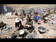 People affected by the earthquake prepare lunch in the town of Gyegu in Yushu County, Qinghai province, April 18, 2010. [Xinhua]