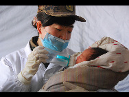 A nurse feeds a four-day-old baby at a temporary medical center established by PLA 536 hospital in Yushu, Qinghai province. April 18, 2010. The baby was born on the early morning April 14, hours before the earthquake. Her mother, two-year-old brother and three-year-old sister died in the earthquake while her father was badly injured and hospitalized. Her aunt brought her to the medical center. [Xinhua] 
