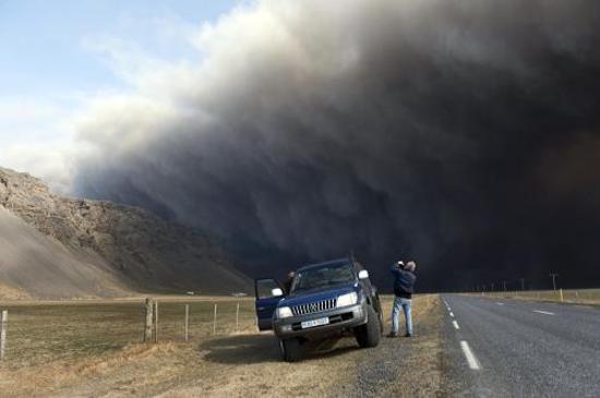 A motorist takes pictures as the Eyjafjallajokull volcano continues to billow smoke and ash during an eruption on April 17, 2010.[Xinhua]