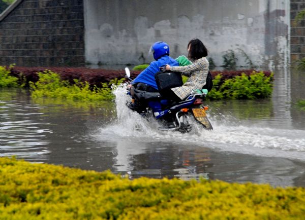  A couple motorists brave their way to go through a flooded pass under a bridge after a sustaining rainfall since Saturday in downtown Huainan city, east China's Anhui Province, April 19, 2010.[Xinhua]