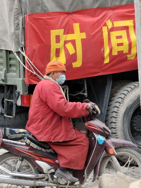 A monk rides a motorcycle past the truck transporting relief supplies in Gyegu Town, the quake-hit Tibetan Autonomous Prefecture of Yushu, in northwest China's Qinghai Province, April 17, 2010.