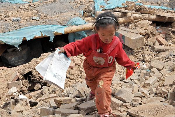 One of the daughters of Ngot (transliterated) finds a textbook from the debris in Gyegu Town of the Tibetan Autonomous Prefecture of Yushu, northwest China's Qinghai Province, April 17, 2010.