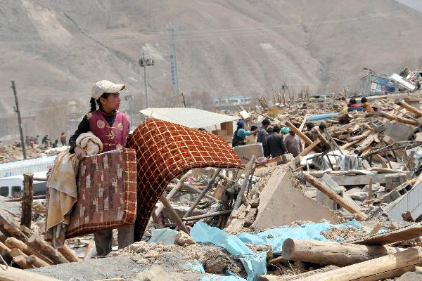 The elder daughter of Ngot (transliterated) looks for belongings on the debris of their home in Gyegu Town of the Tibetan Autonomous Prefecture of Yushu, northwest China's Qinghai Province, April 17, 2010.