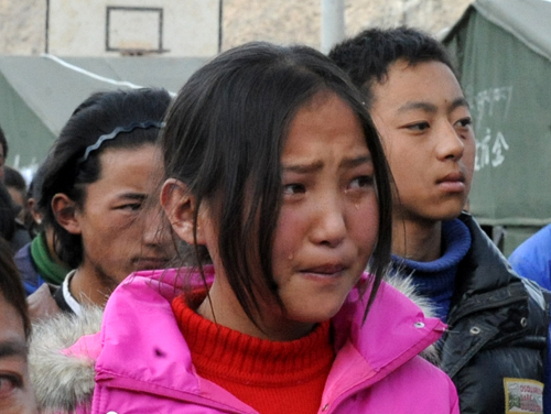 A girl cries during a ceremony for returning to school in front of tents used as classrooms on the first school day since the April 14 earthquake in Yushu, Qinghai, April 18, 2010. 