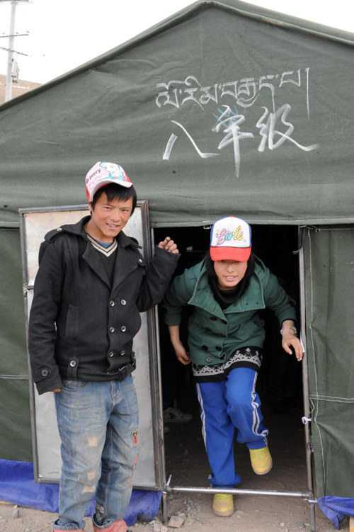 Two students leave a tent used as a classroom on the first school day since the April 14 earthquake in Yushu, Qinghai, April 18, 2010. The Chinese character and Tibetan on the tent read “Eighth grade.”[