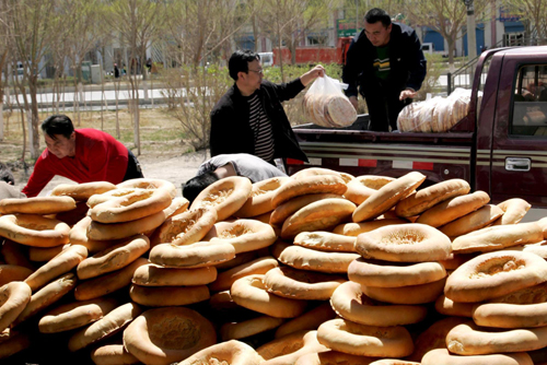 People load Nang (baked crusty pancake) sacks onto a car before transporting them to quake-hit Yushu in Hami, Northwest China’s Xinjiang Uygur autonomous region, April 18, 2010.