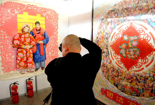 A visitor takes photos of a New Year picture at the 3rd China Culture and Art Expo in Weifang, Shandong Province, April 18, 2010. 