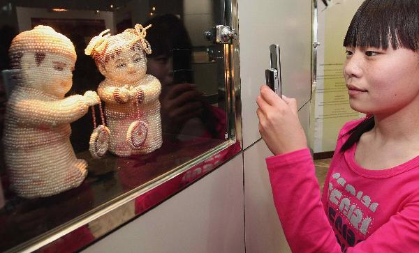 A visitor takes photos of pearl exhibits at the 7th China International Pearl Festival kicked off in Huadong International Jewelry City, a jewelry shopping center, in Shanxiahu Township in Zhuji City, east China's Zhejiang Province, April 18, 2010. (Xinhua)