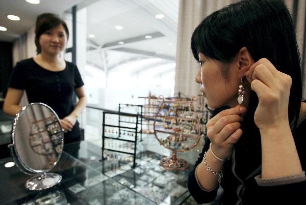 A woman tries a pearl pendant at the 7th China International Pearl Festival kicked off in Huadong International Jewelry City, a jewelry shopping center, in Shanxiahu Township in Zhuji City, east China's Zhejiang Province, April 18, 2010. (Xinhua)