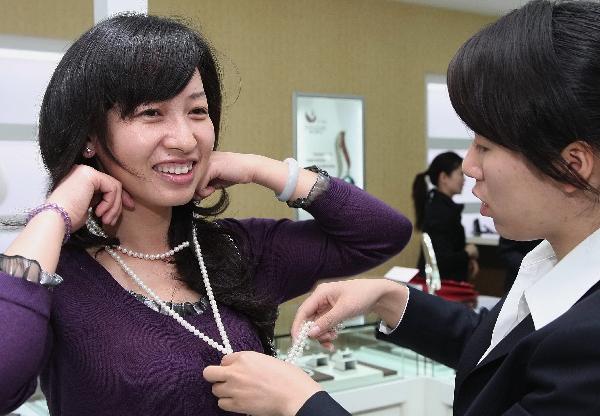 A woman tries a pearl necklace at the 7th China International Pearl Festival kicked off in Huadong International Jewelry City, a jewelry shopping center, in Shanxiahu Township in Zhuji City, east China's Zhejiang Province, April 18, 2010. (Xinhua)