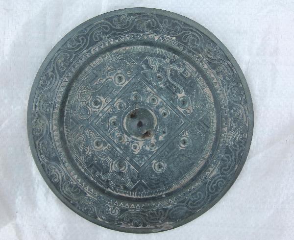 Photo taken on April 17, 2010 shows a bronze mirror excavated from an ancient tomb in Xiangfan City, central China's Hubei Province. An ancient tomb of middle and late Eastern Han Dynasty (25-220) has been discovered at a construction site in Xiangzhou Industrial Garden in Xiangfan City recently. (Xinhua/An Fubin)