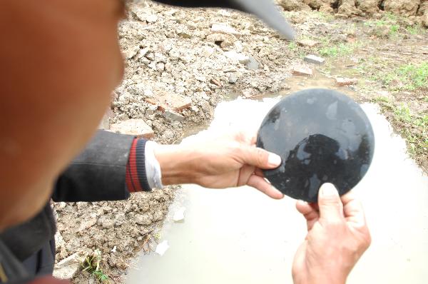 A staff worker from the Cultural Relics and Archaeology Institute of Xianfan City checks a bronze mirror excavated from an ancient tomb in Xiangfan City, central China's Hubei Province, April 17, 2010. An ancient tomb of middle and late Eastern Han Dynasty (25-220) has been discovered at a construction site in Xiangzhou Industrial Garden in Xiangfan City recently. (Xinhua/An Fubin)