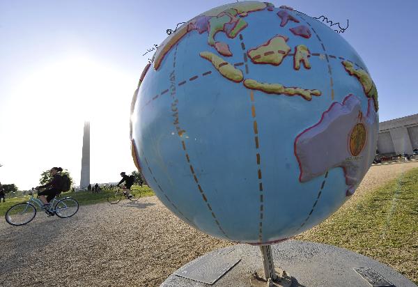 A man passes an earth model in Washington D.C., the United States, April 19, 2010. A massive Climate Rally will be held in the US capital on Sunday to commemorate the 40th anniversary of Earth Day. [Xinhua]