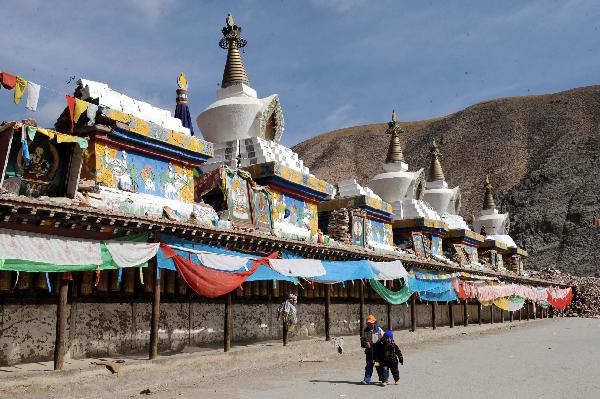 Children walk by the Gyanak Marnyi stones, about 2 kilometers from the quake-hit Gyegu Town of Yushu Tibetan Autonomous Prefecture of northwest China's Qinghai Province, April 19, 2010. 