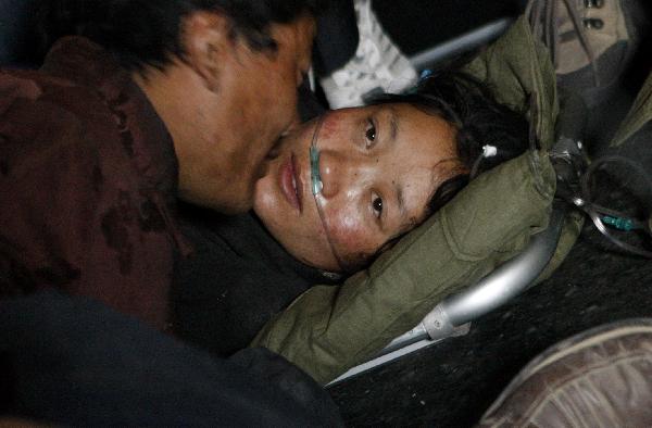 Cering Wangde(L) comforts his wife in an aircraft heading to Xining for treat in Yushu, northwest China's Qinghai Province, April 19, 2010.