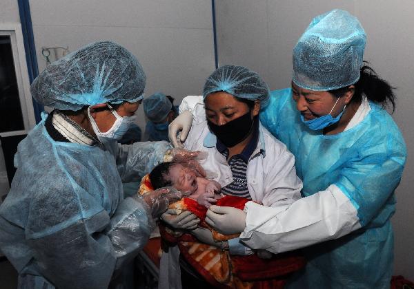 Nurses hold a newborn baby at a makeshift shelter in Yushu County, northwest China's Qinghai Province, on April 19, 2010. 